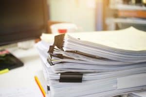 Stack of papers files on work desk in office, business report paper or piles of unfinished documents achives with clips on offices desk, Business concept
